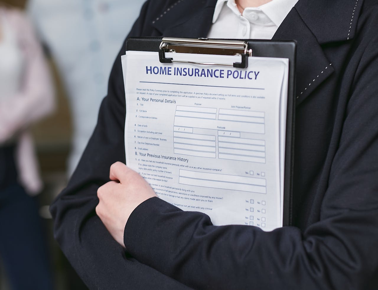 services-03 Close-up of a person holding a home insurance policy on a clipboard, captured indoors.